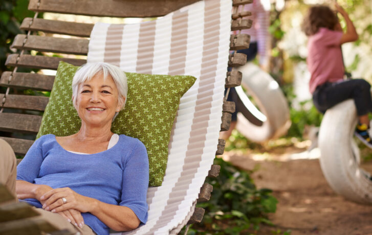 Seniorka relaxující v houpací síti na zahradě